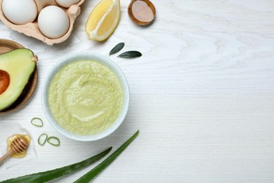 Homemade hair mask in bowl and ingredients on white wooden table, flat lay. Space for text