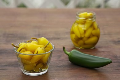 Fresh and pickled jalapeno peppers on wooden table