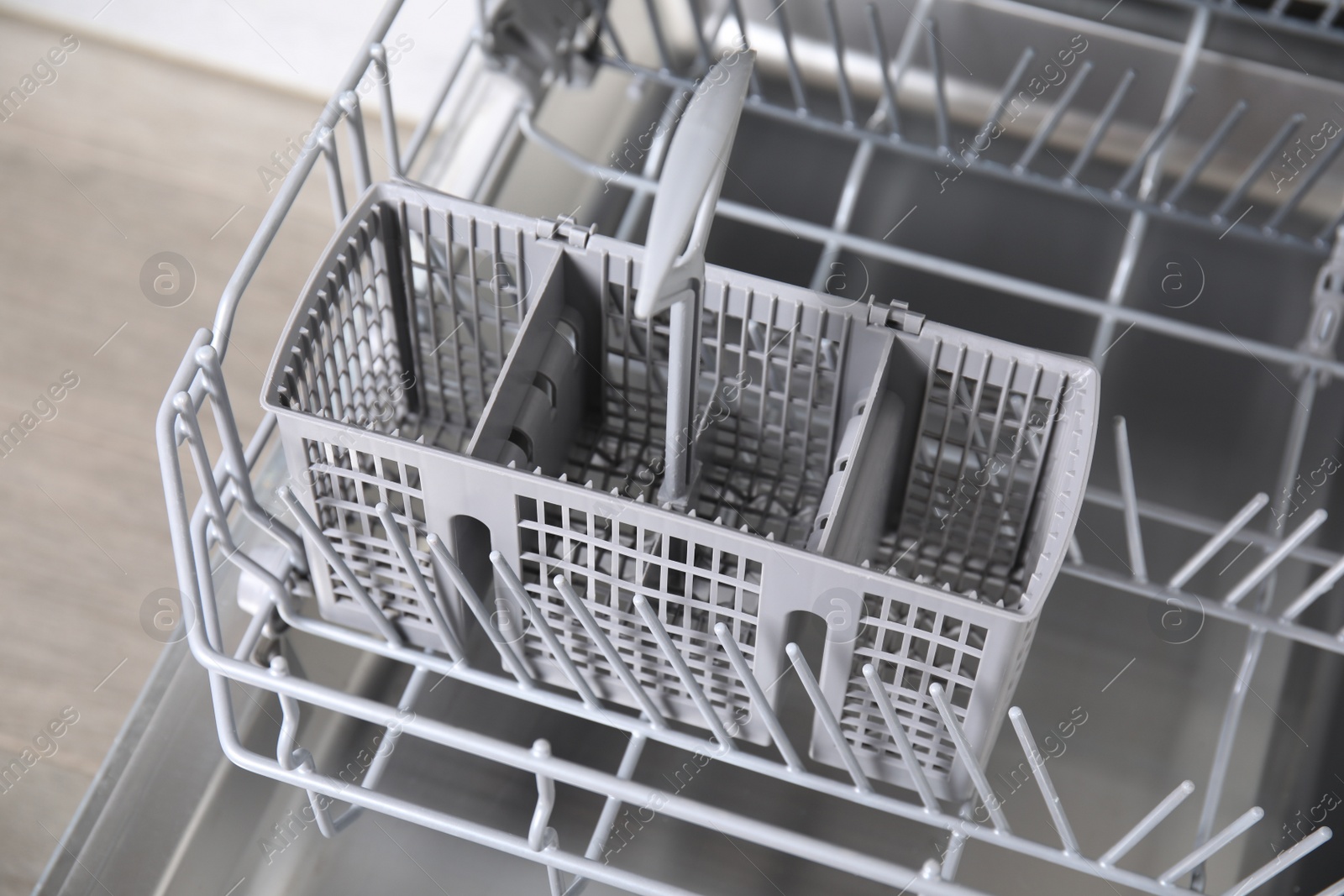 Photo of Open clean empty dishwasher in kitchen, closeup