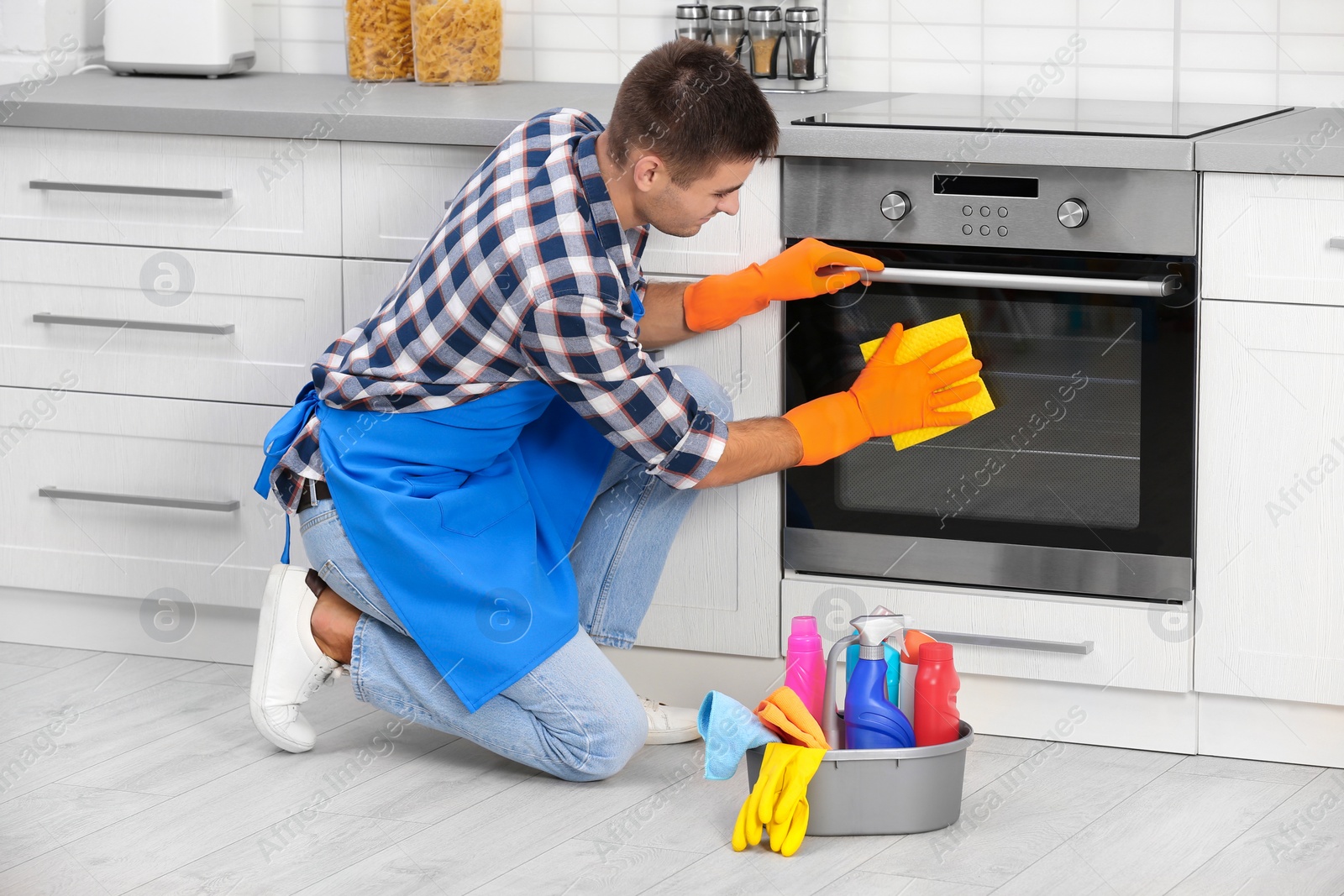 Photo of Man cleaning kitchen oven with rag in house