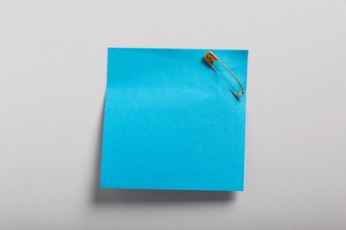 Photo of Blue paper note attached with safety pin on white background
