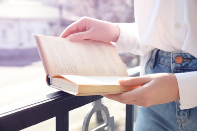 Photo of Woman reading book outdoors on sunny day, closeup