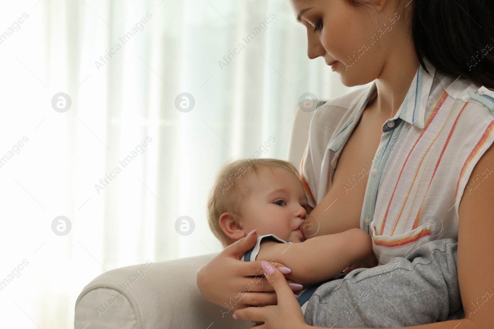 Photo of Woman breastfeeding her little baby at home