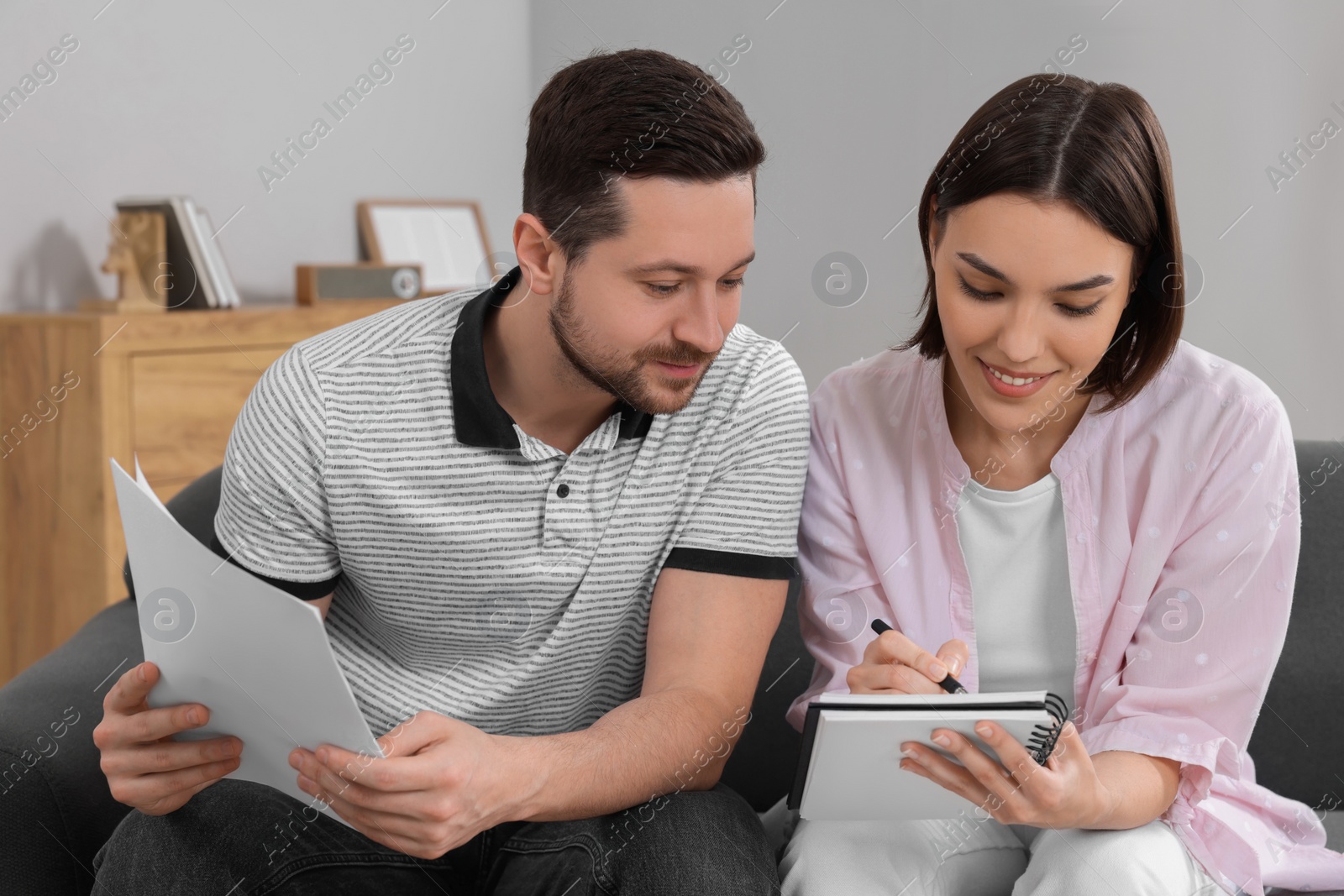 Photo of Young couple with papers discussing pension plan indoors