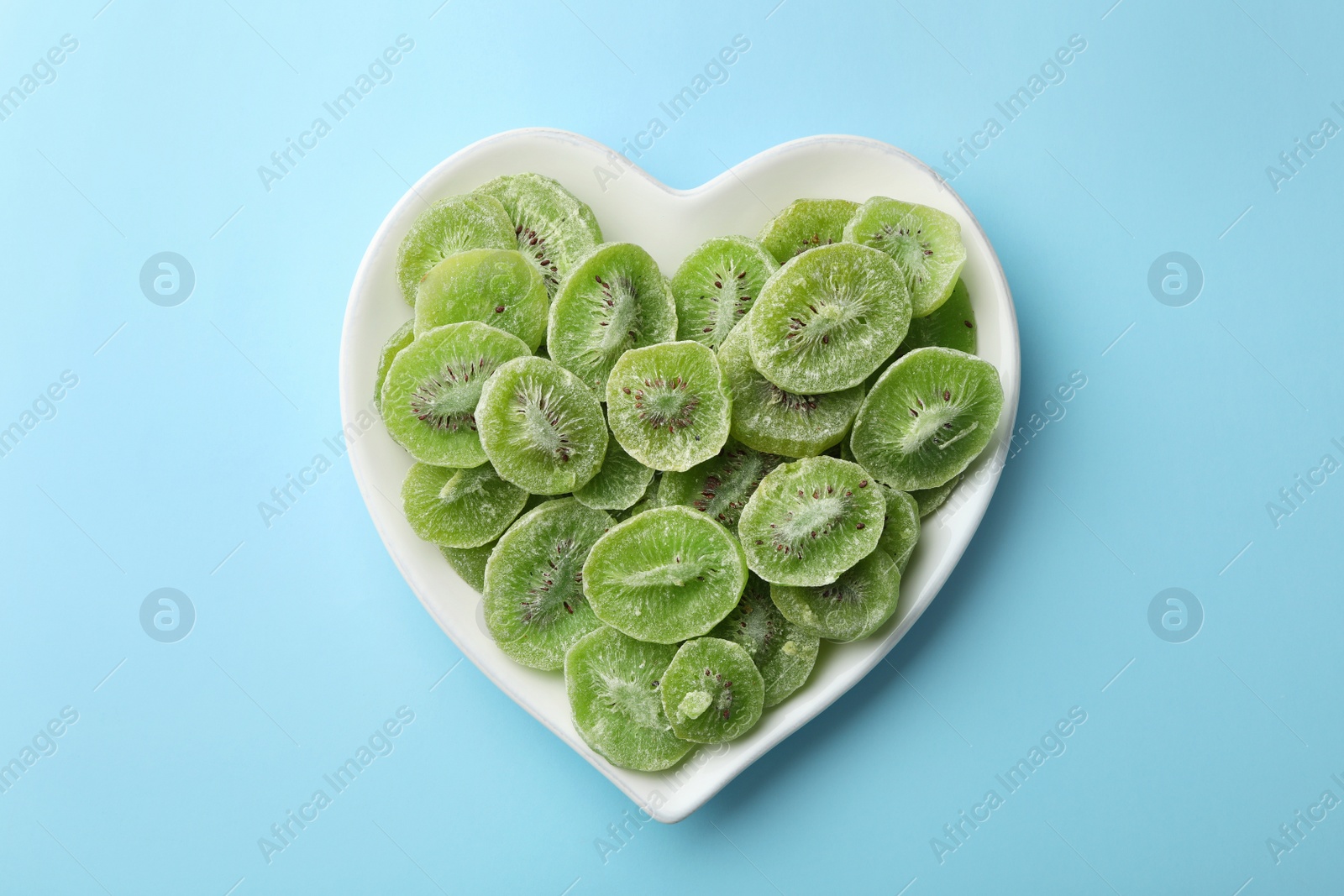 Photo of Plate with slices of kiwi on color background, top view. Dried fruit as healthy food