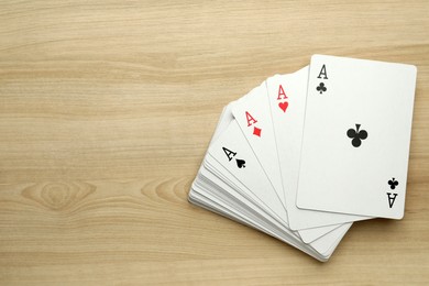 Photo of Four aces playing cards on wooden table, flat lay. Space for text