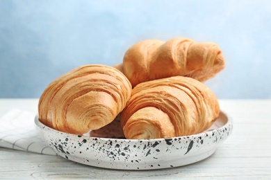 Plate with tasty croissants on table