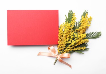 Beautiful mimosa bouquet and blank card on white background, flat lay. Space for text