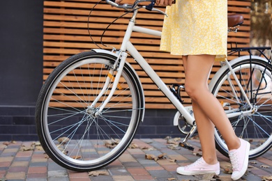 Photo of Woman with bicycle on street against wooden wall, closeup