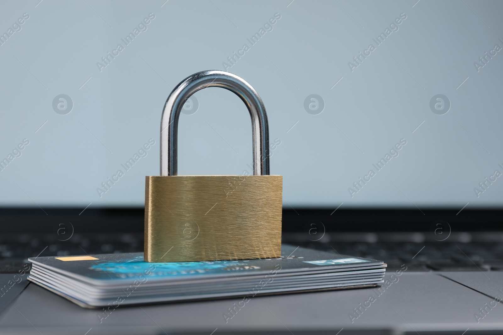 Photo of Cyber security. Metal padlock and credit cards on laptop, closeup. Space for text