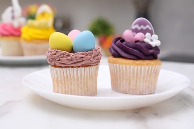 Tasty decorated Easter cupcakes on white marble table, closeup