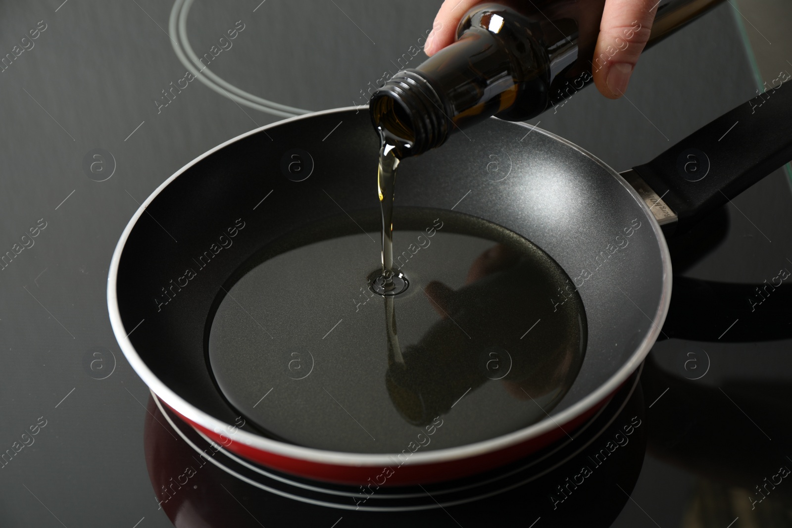 Photo of Woman pouring cooking oil from bottle into frying pan, closeup