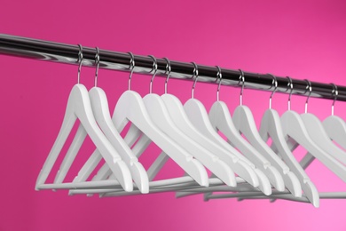 Metal rack with clothes hangers on color background