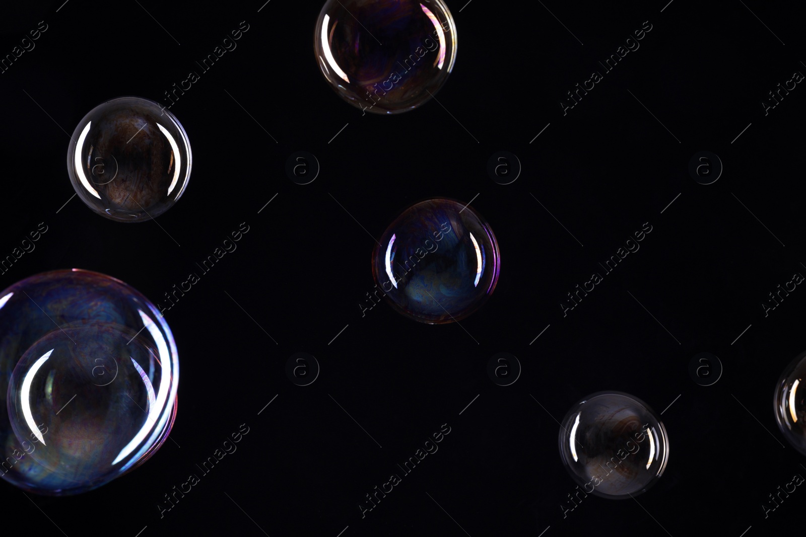 Photo of Many beautiful soap bubbles on black background