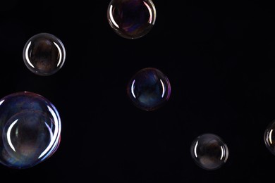 Photo of Many beautiful soap bubbles on black background