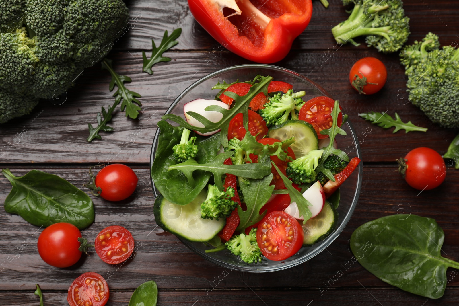 Photo of Tasty fresh vegetarian salad on dark wooden table, flat lay