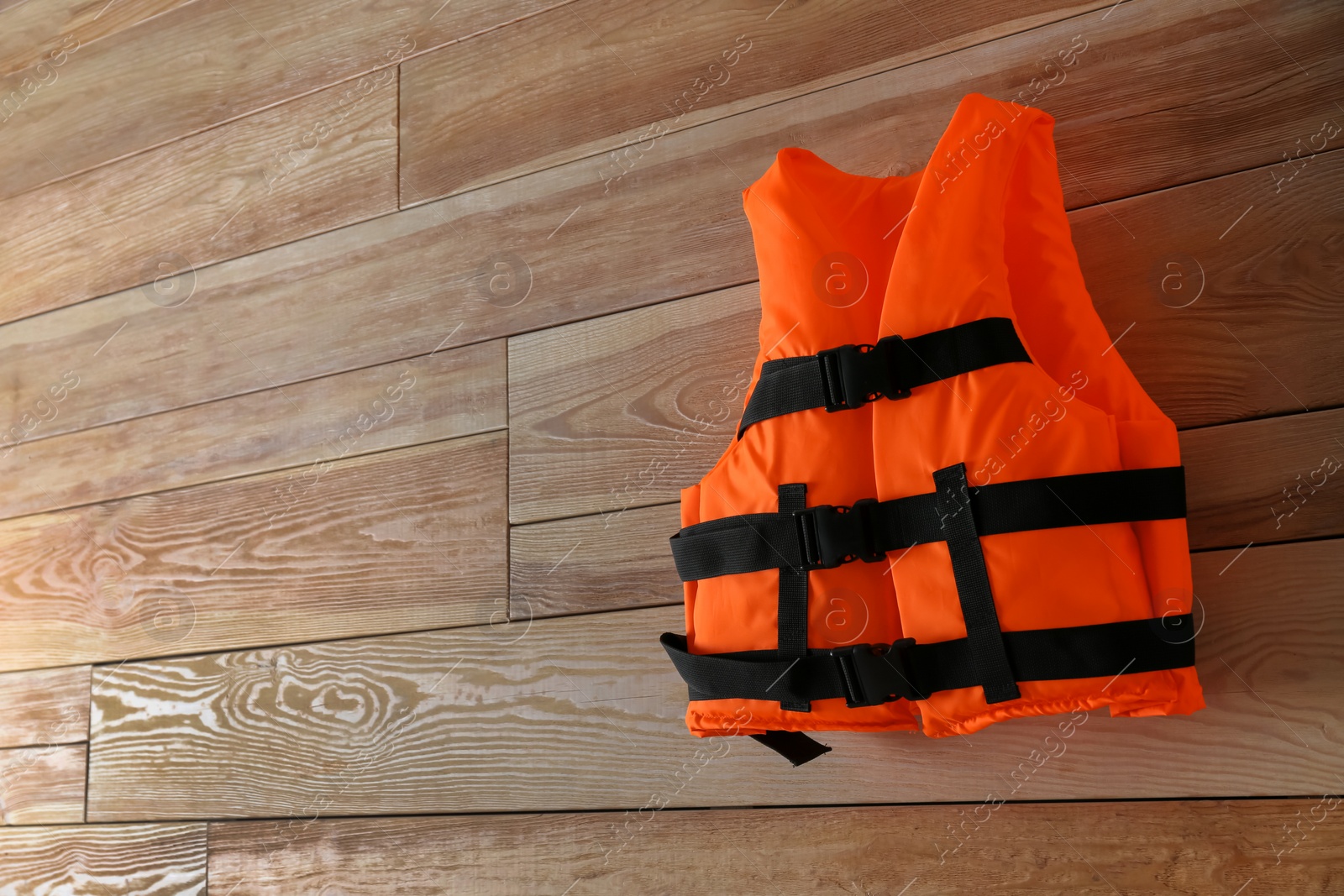 Photo of Orange life jacket on wooden background. Space for text