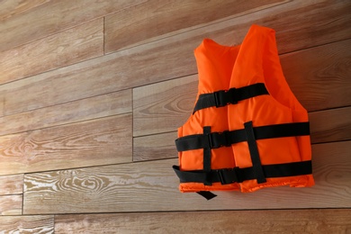 Photo of Orange life jacket on wooden background. Space for text
