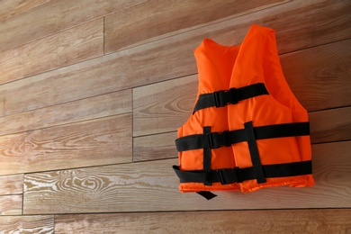 Orange life jacket on wooden background. Space for text