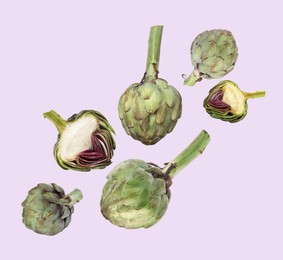 Image of Fresh raw artichokes falling on lavender background