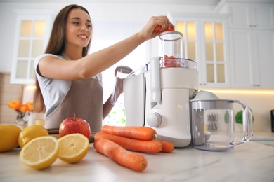 Photo of Young woman making tasty fresh juice at table in kitchen