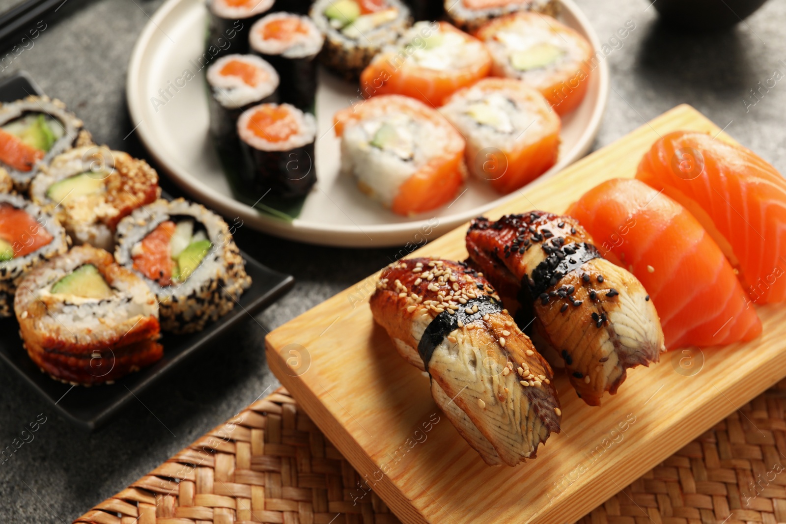Photo of Different tasty sushi rolls on dark grey table