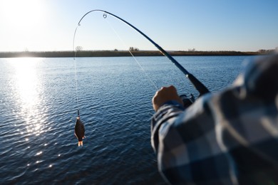 Photo of Fisherman catching fish with rod at riverside, closeup