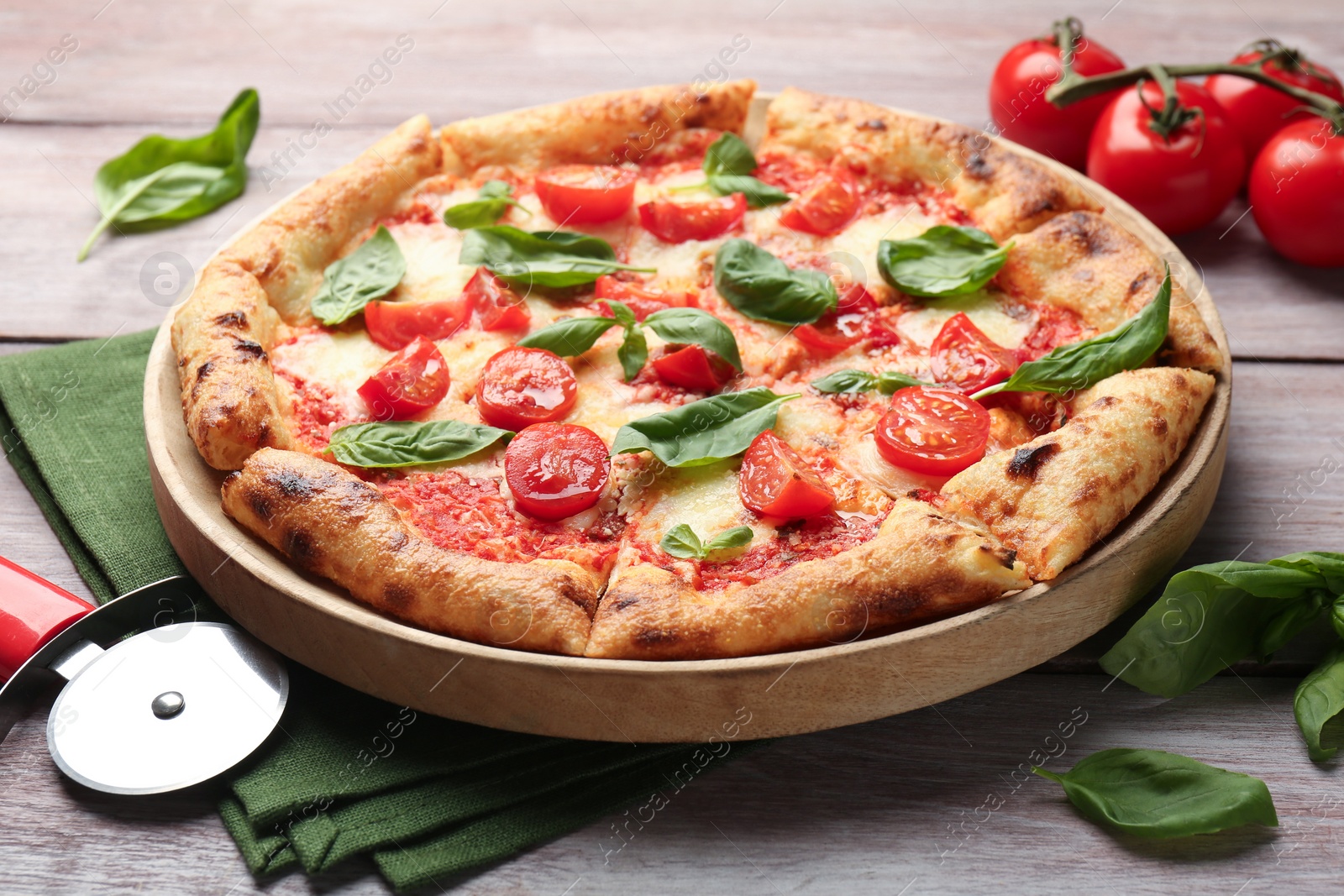 Photo of Delicious Margherita pizza and cutter on wooden table, closeup