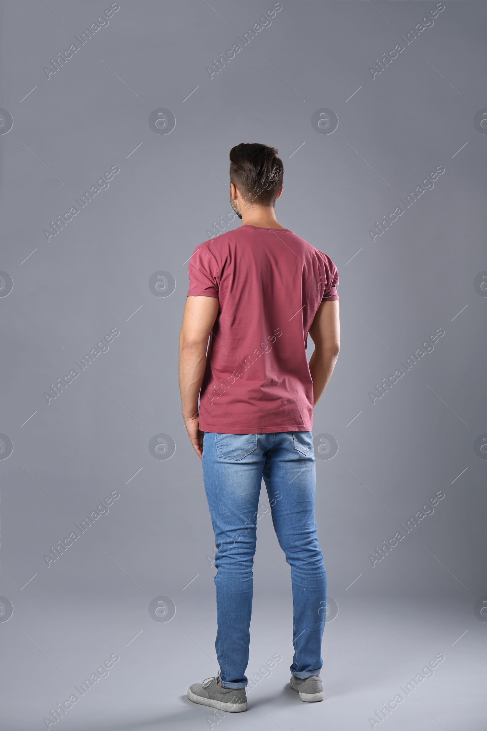 Photo of Young man in stylish jeans on grey background