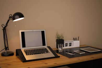 Photo of Modern workplace interior with laptop and devices on table. Space for text