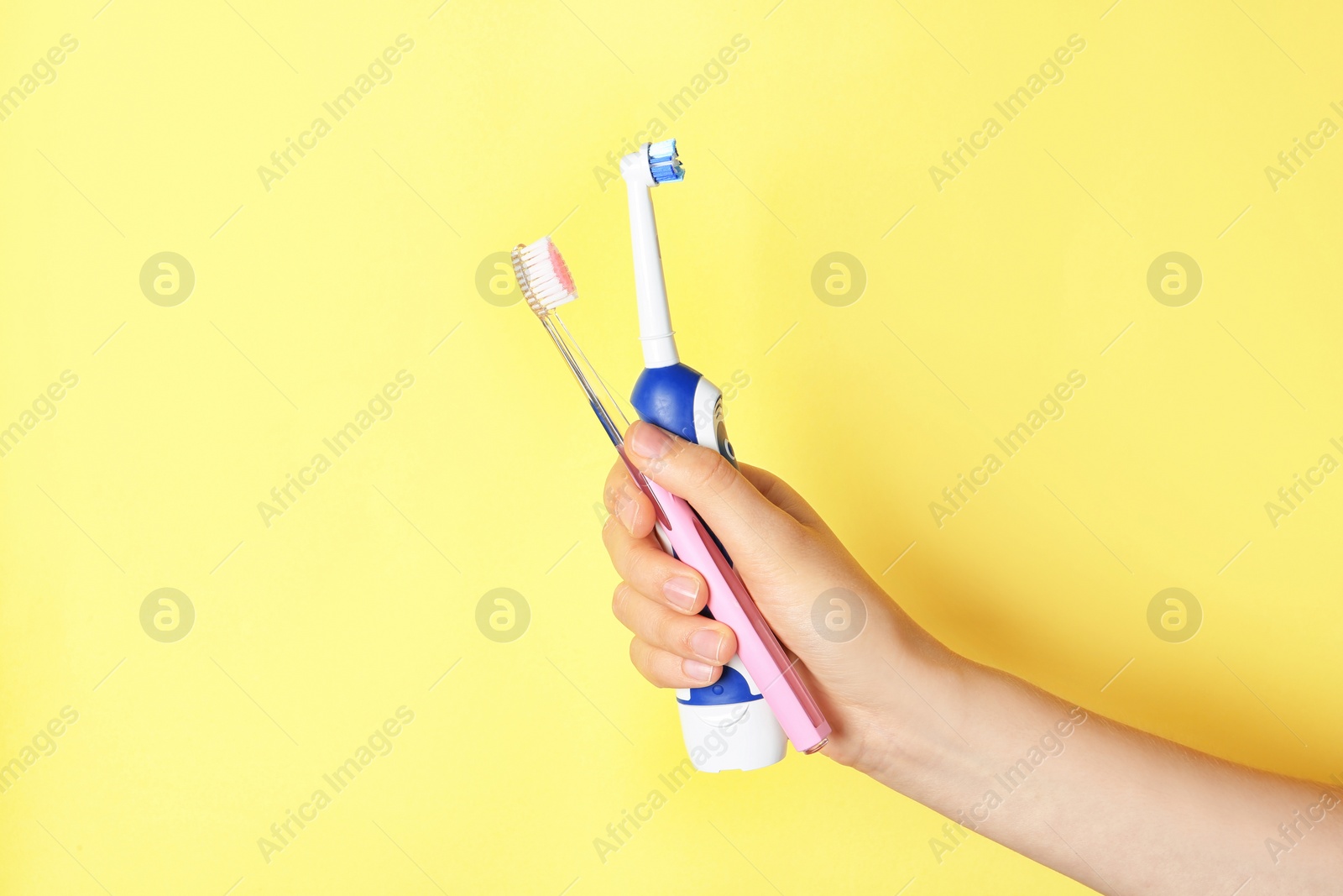 Photo of Woman holding manual and electric toothbrushes against color background