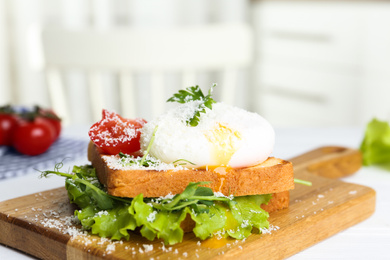 Photo of Delicious poached egg sandwich served on wooden board, closeup
