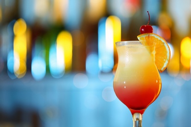 Photo of Glass of fresh alcoholic cocktail against blurred background. Space for text