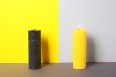 Decorative candles on table against color background