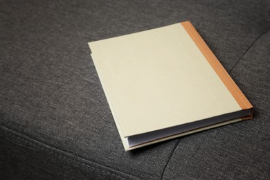Photo of Hardcover book on grey sofa, closeup view