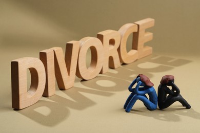 Photo of Word Divorce made of wooden letters and plasticine people figures on beige background