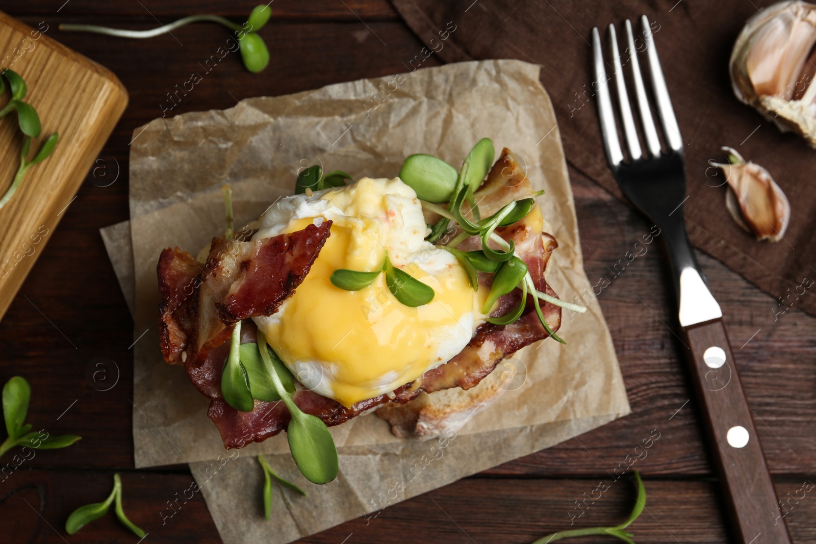 Photo of Delicious egg Benedict served on wooden table, flat lay