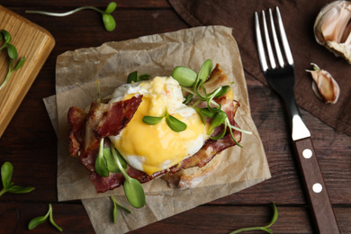 Photo of Delicious egg Benedict served on wooden table, flat lay