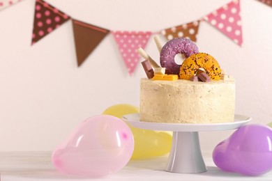 Photo of Delicious cake decorated with sweets and balloons on white wooden table, space for text