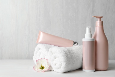 Different hair products, towel and comb on white wooden table