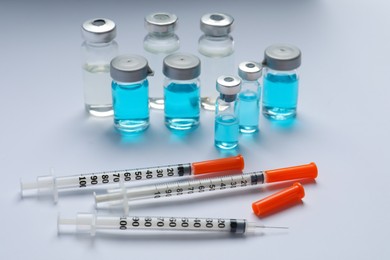 Photo of Disposable syringes with needles and vials on white background
