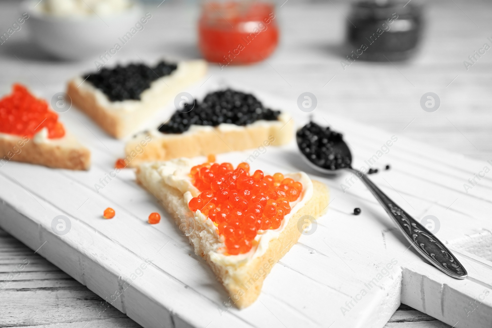 Photo of Sandwiches with black and red caviar on wooden board