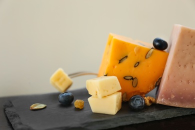 Different types of delicious cheeses on slate plate, closeup. Space for text