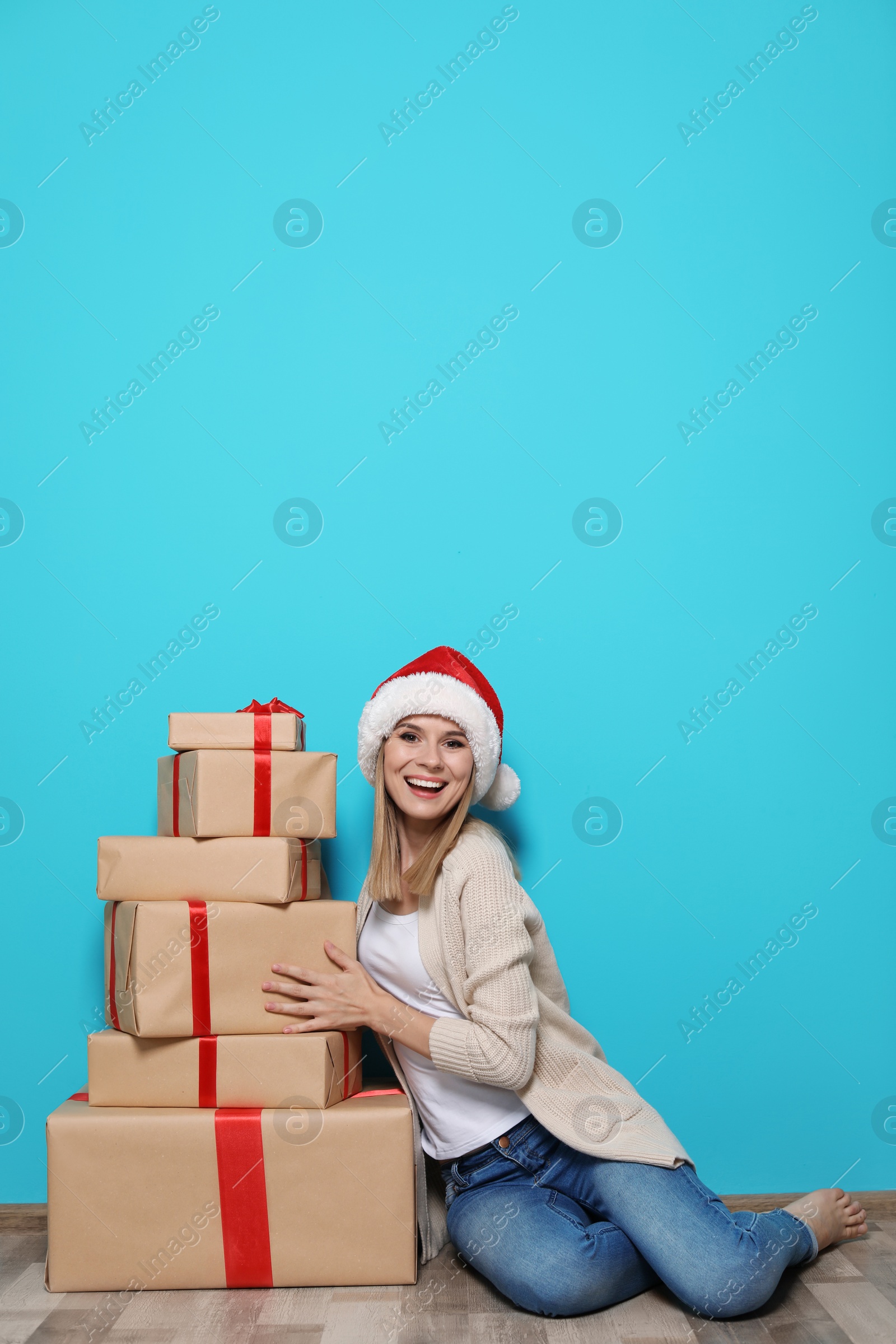 Photo of Young woman with Christmas gifts near color wall