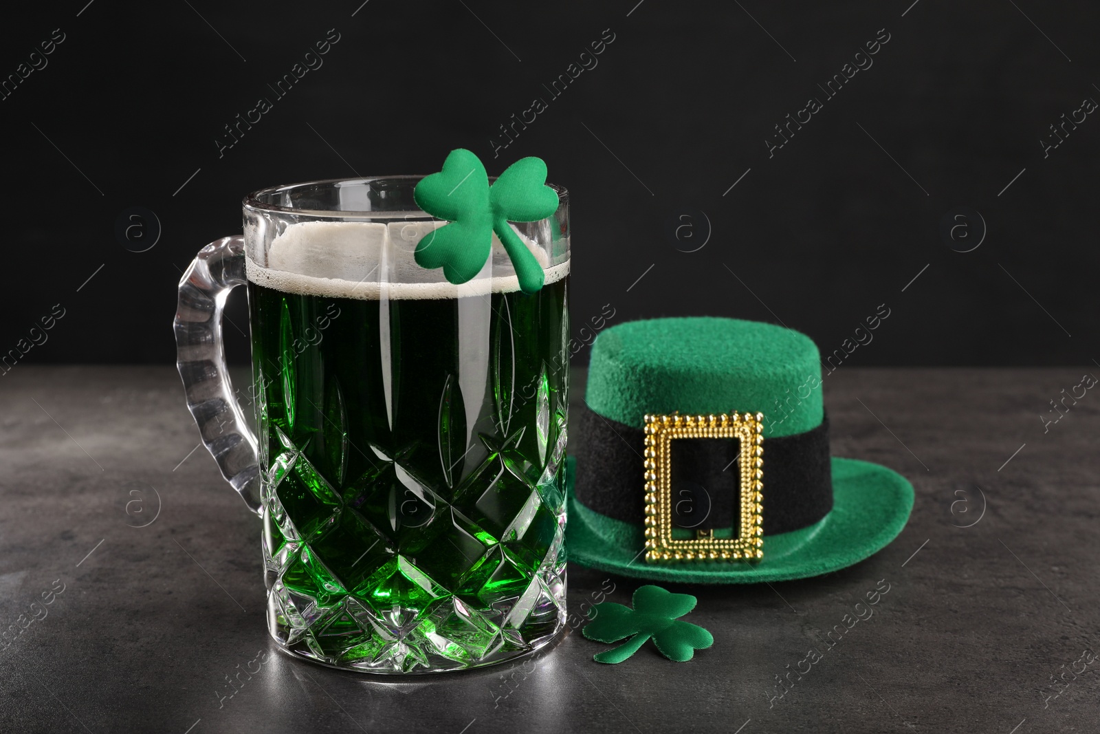 Photo of St. Patrick's day celebration. Green beer, leprechaun hat and decorative clover leaves on grey table. Space for text