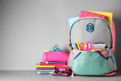 Photo of Stylish backpack with different school stationery on table against light grey background. Space for text