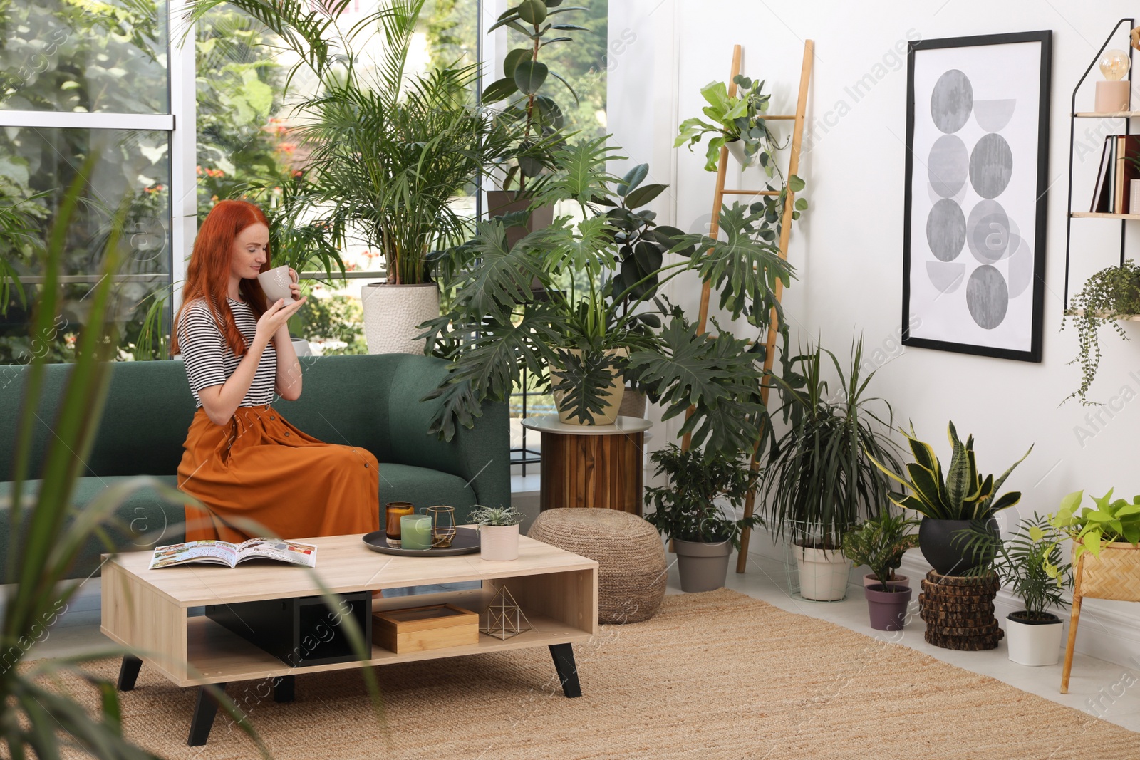 Photo of Beautiful woman with cup of tea resting on sofa in room