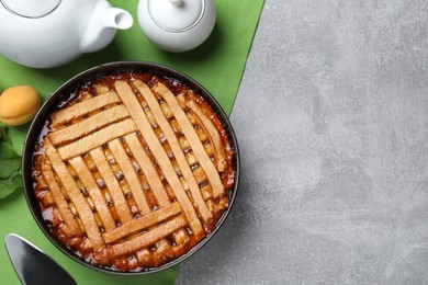 Photo of Delicious apricot pie in baking dish on grey table, flat lay. Space for text