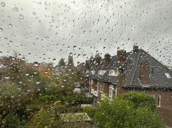 Photo of View on city street through window with water droplets on rainy day, closeup