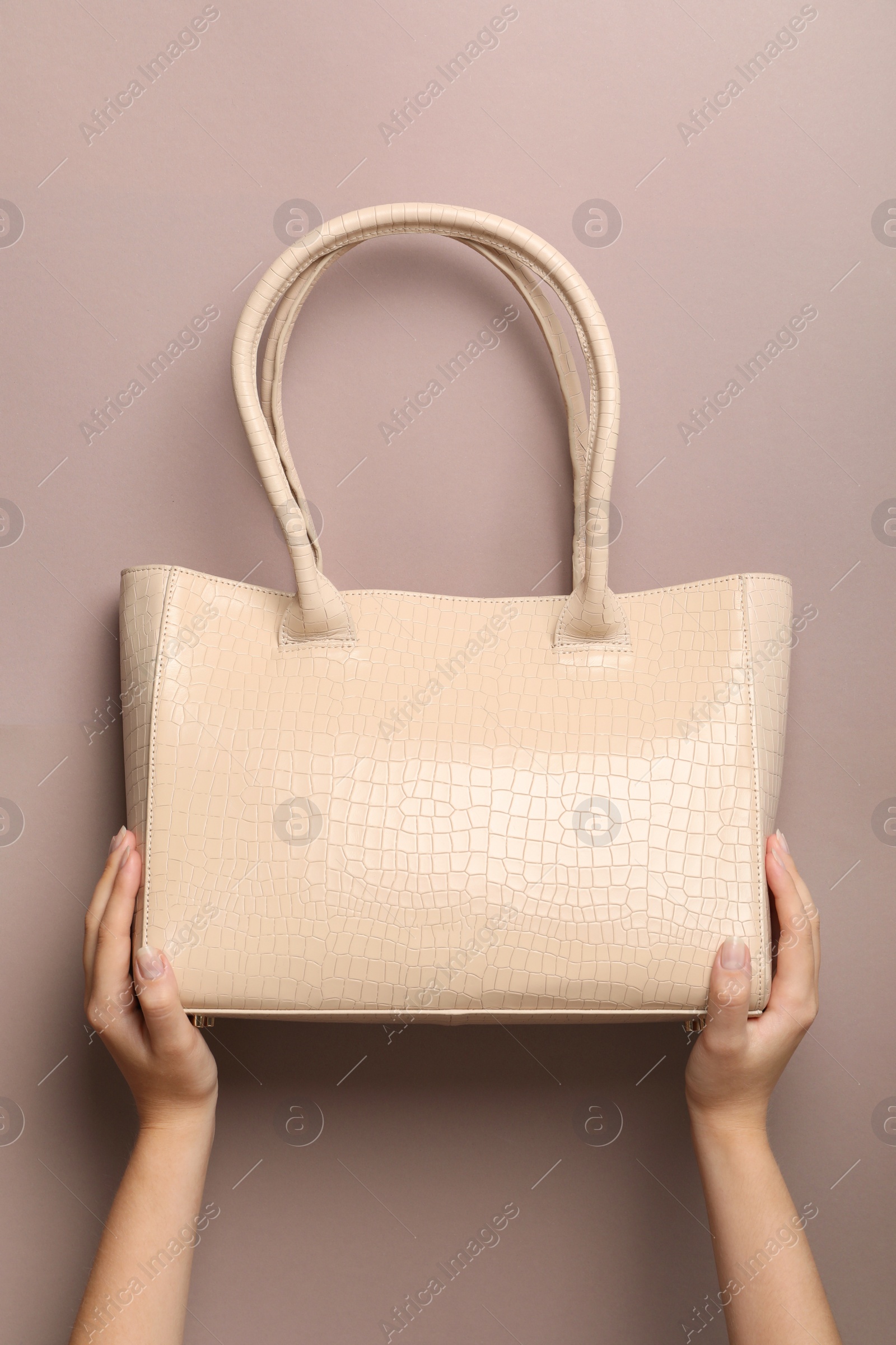 Photo of Woman holding stylish bag on brown background, closeup